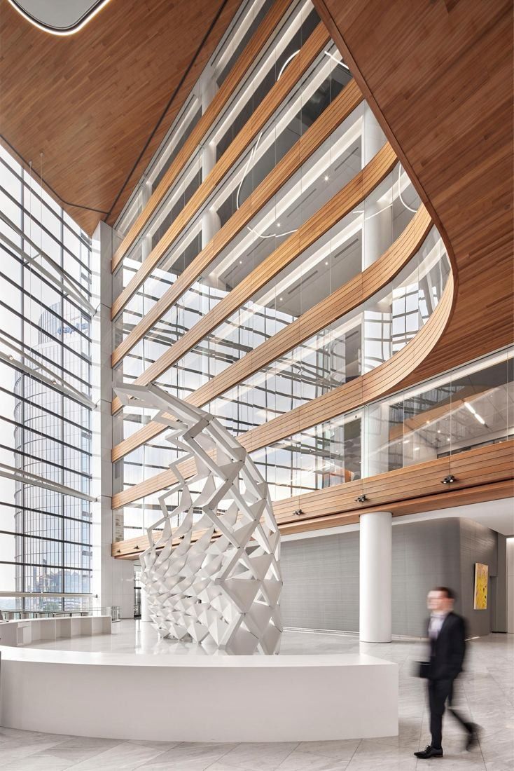 Capital One: White lattice sculpture under curving wood balconies, a blurred figure walking past