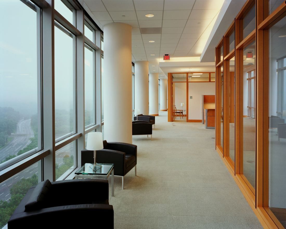 Capital One: Window-lined corridor with leather chairs and wood doors