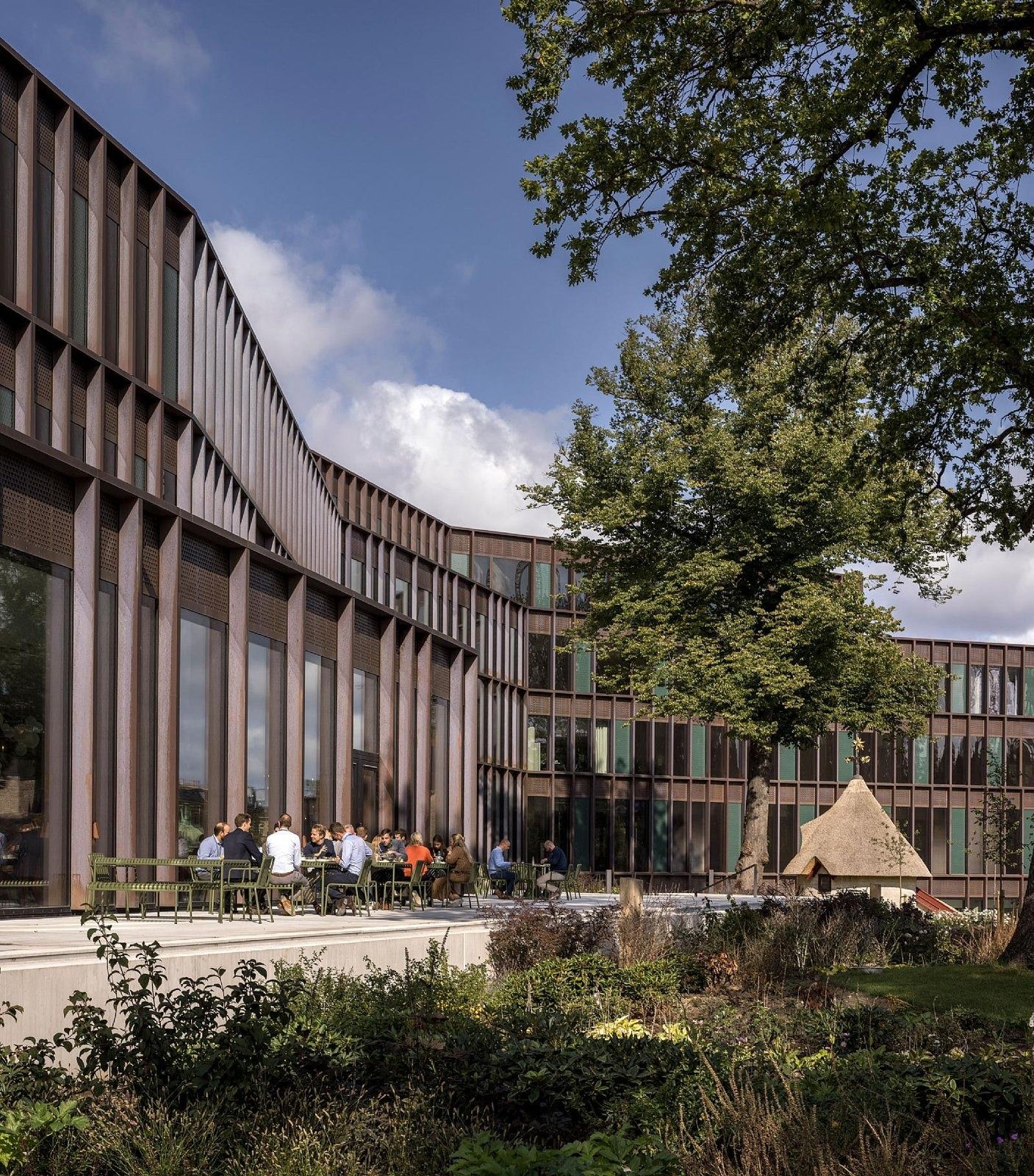 Carlsberg: Copper façade behind garden planting with a tree and a pavilion