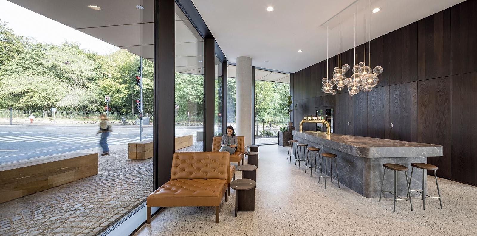 Carlsberg: Lounge with dark wood bar counter, leather armchair and full-height windows to the street