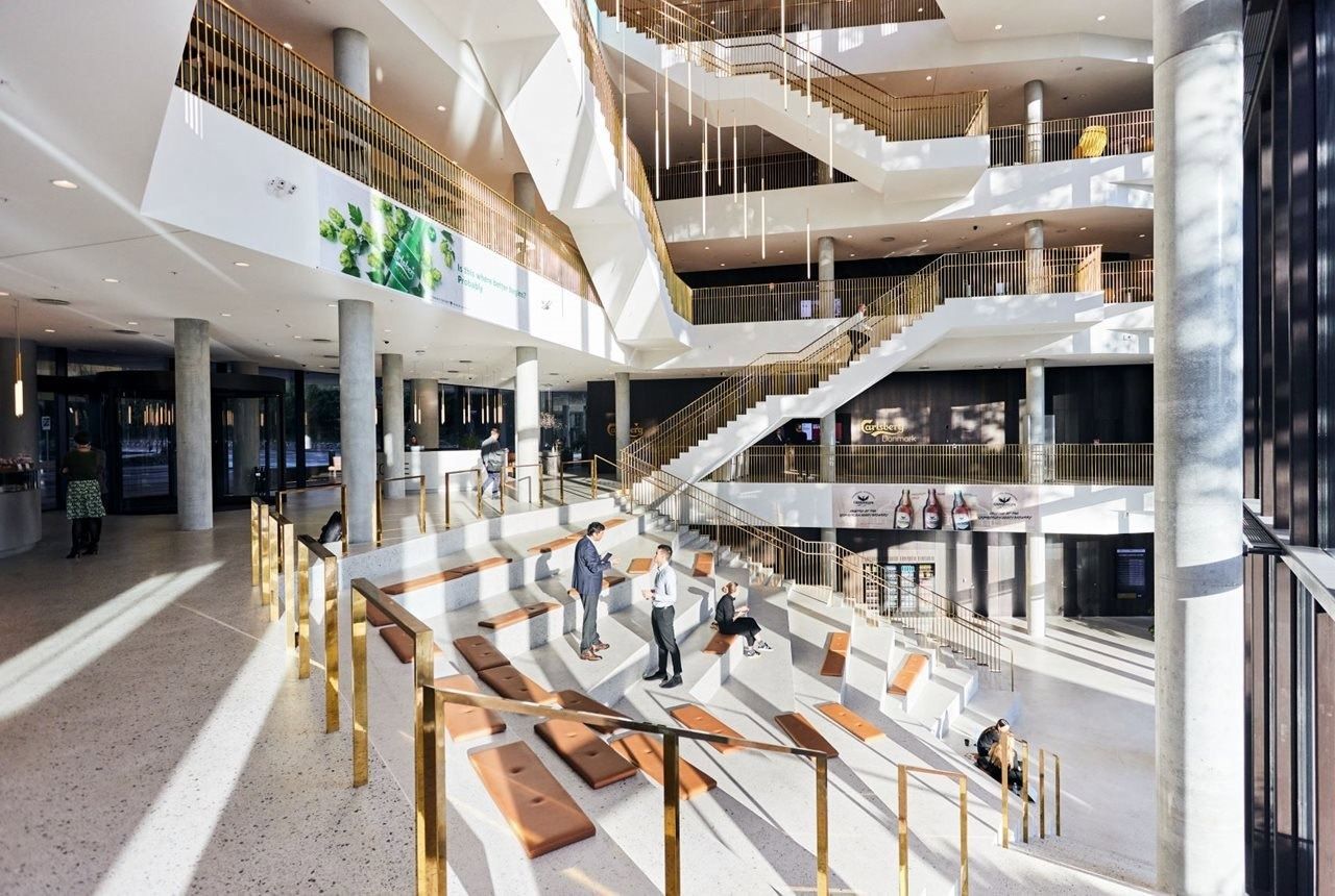 Carlsberg: Multi-storey white atrium with a wide stepped staircase, brass railings and leather seat pads