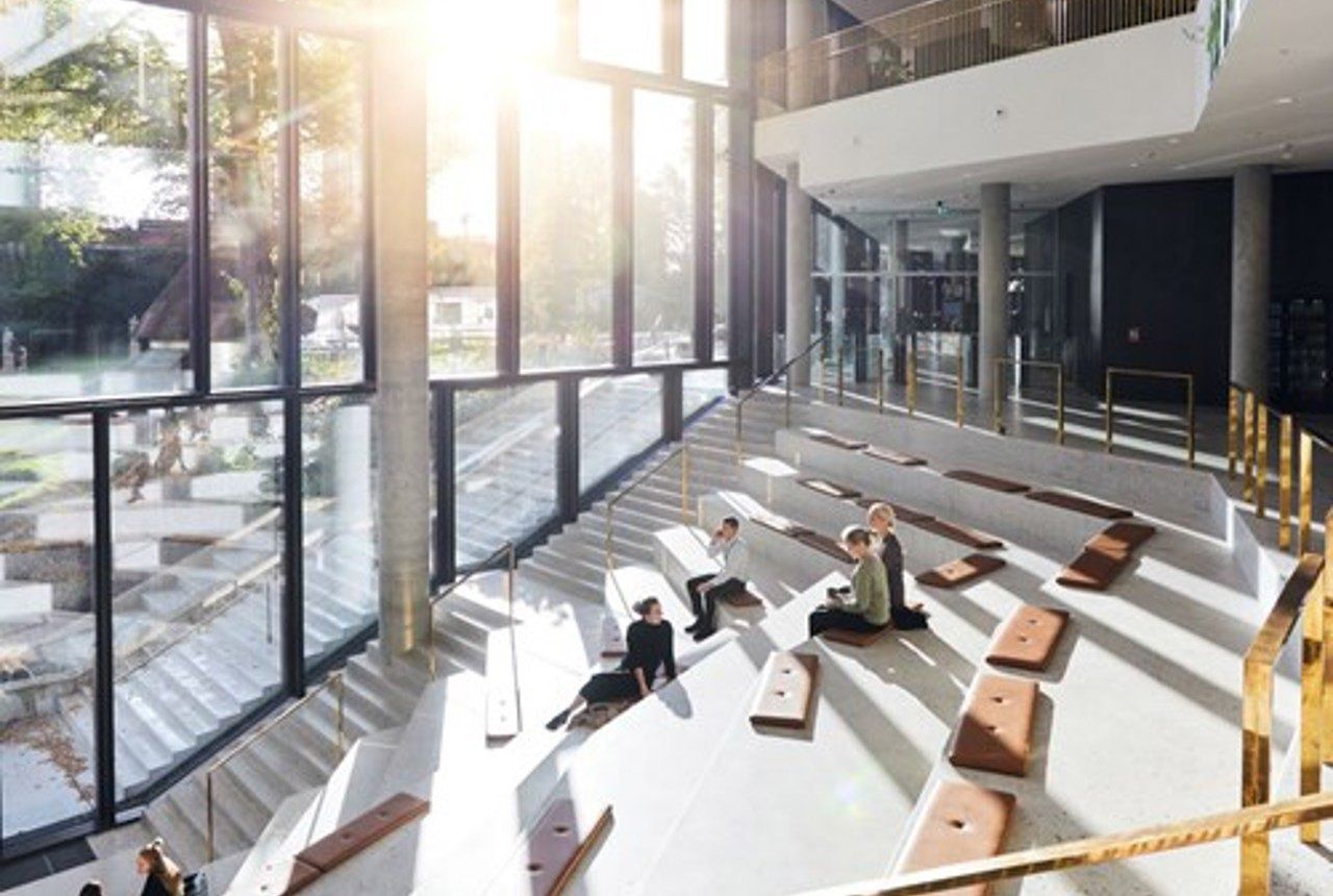 Carlsberg: Sunlit stepped staircase with leather seat pads and people sitting beside tall windows