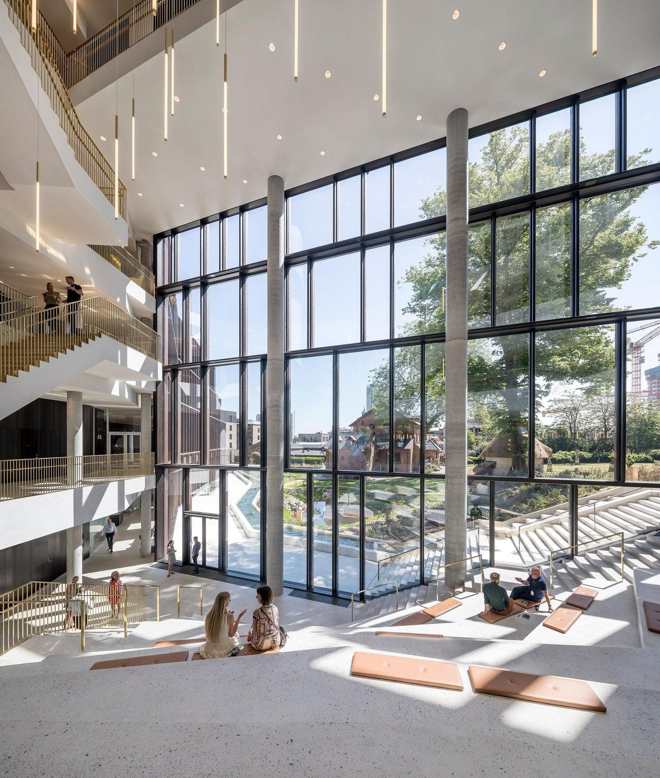 Carlsberg: Tall glazed atrium wall looking out to trees, with sunlit stepped seating inside
