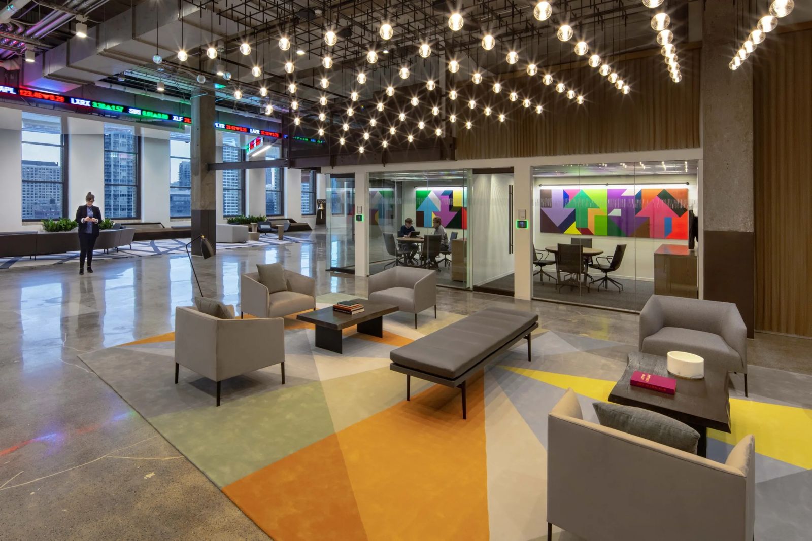 Cboe Global Markets: A big open lounge with rows of hanging lights, armchairs and colourful glass rooms