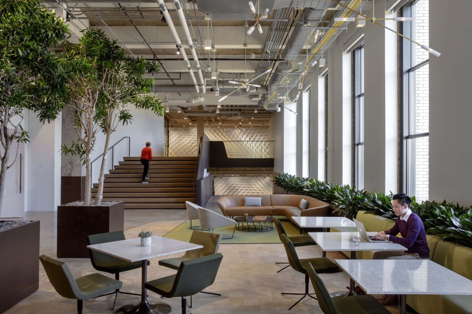 Cboe Global Markets: A café area with trees, white tables and a wide wooden stair under an exposed ceiling