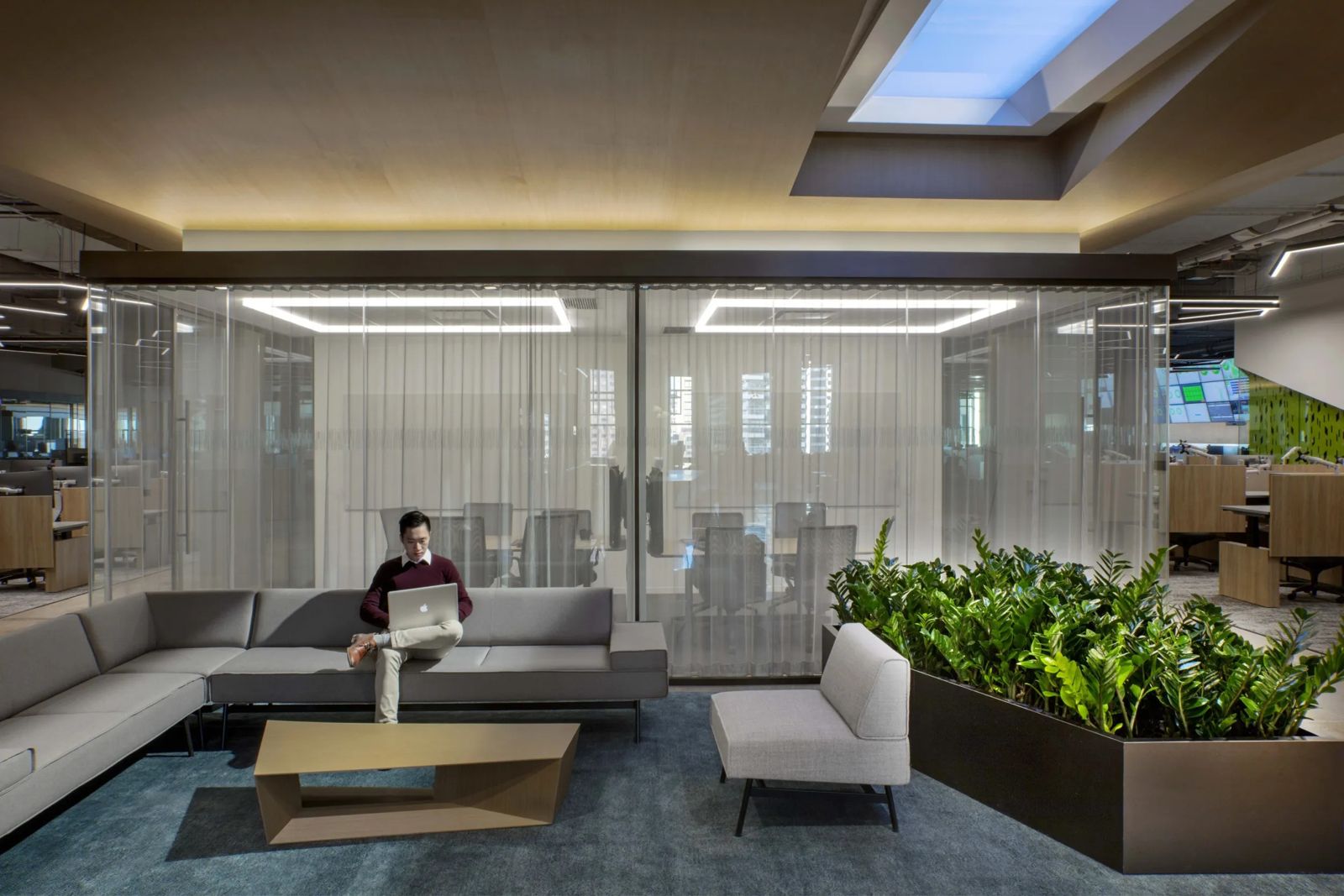 Cboe Global Markets: A man working on a sofa in front of glass meeting rooms and planters