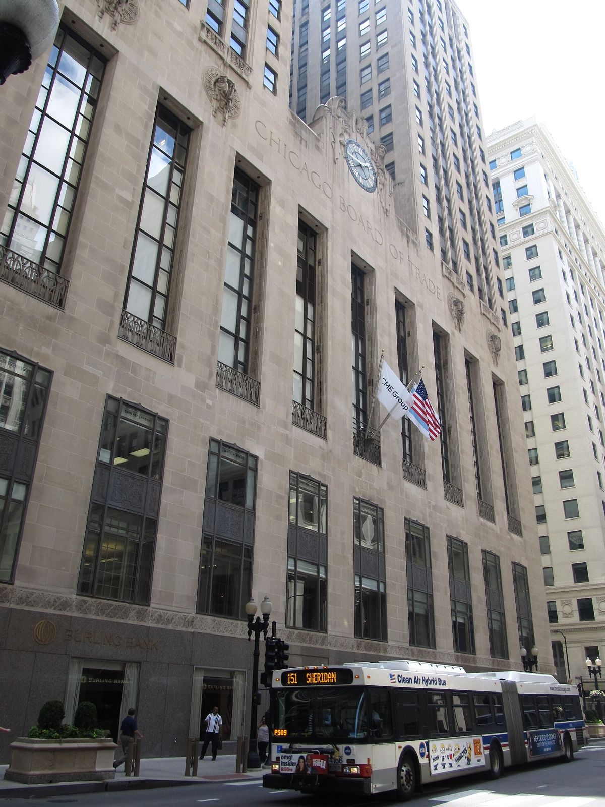A tall Art Deco stone skyscraper rising above a busy street
