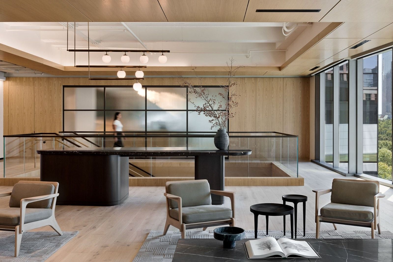 CBRE: A calm reception with a dark desk, armchairs and pale wood walls