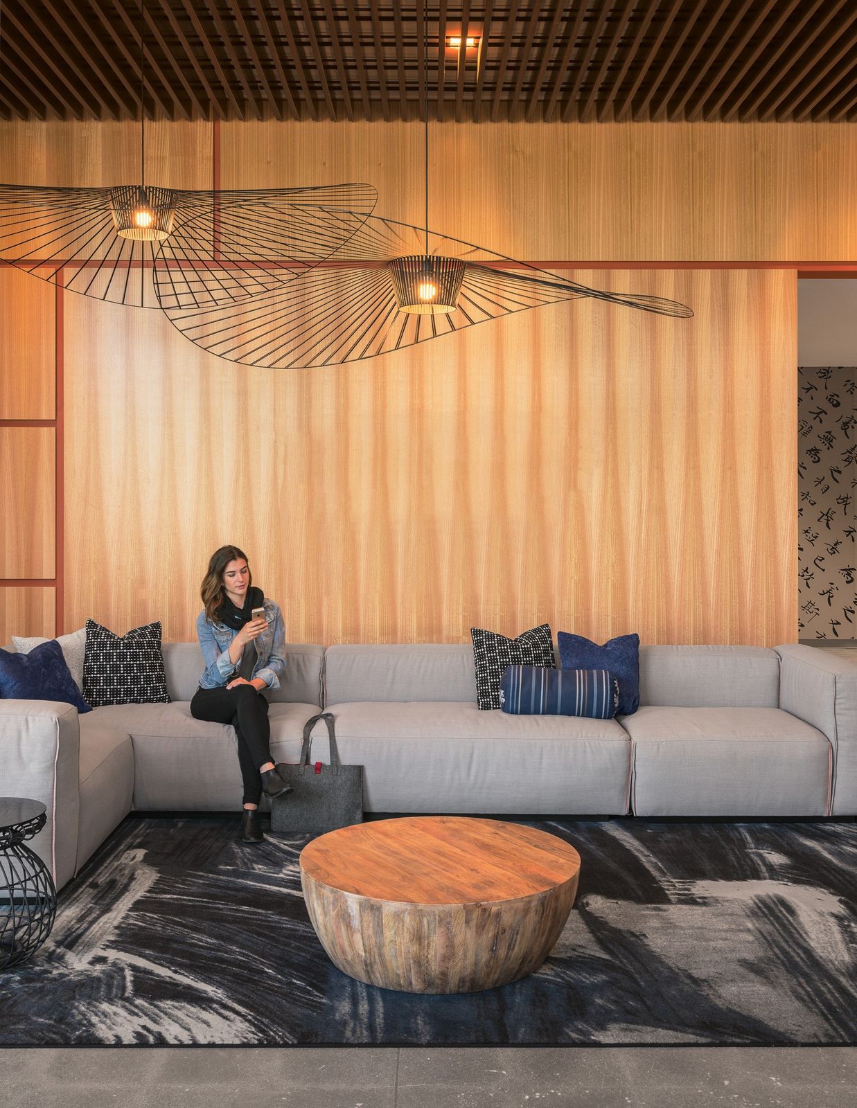 Cisco: A sofa under a wooden wall and a woven pendant lamp