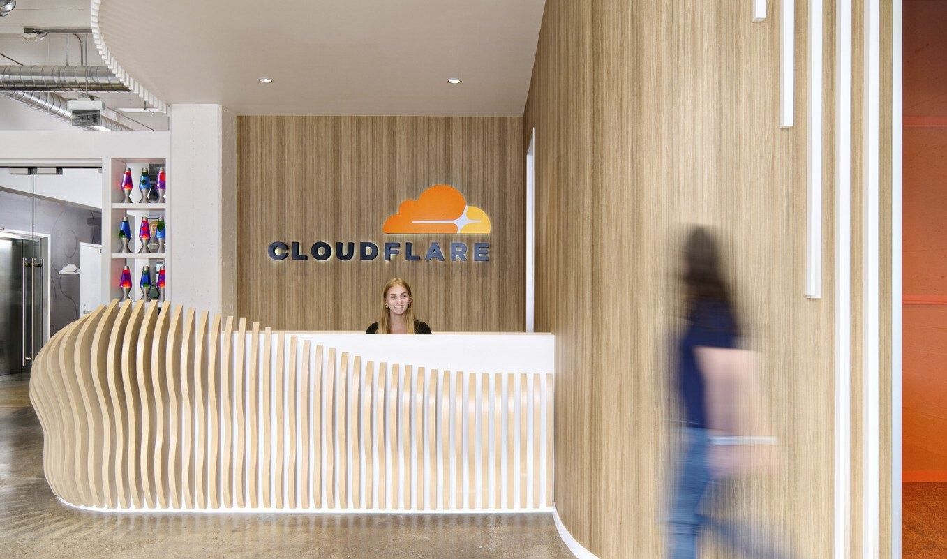 Cloudflare: A curving wooden reception desk below the Cloudflare logo
