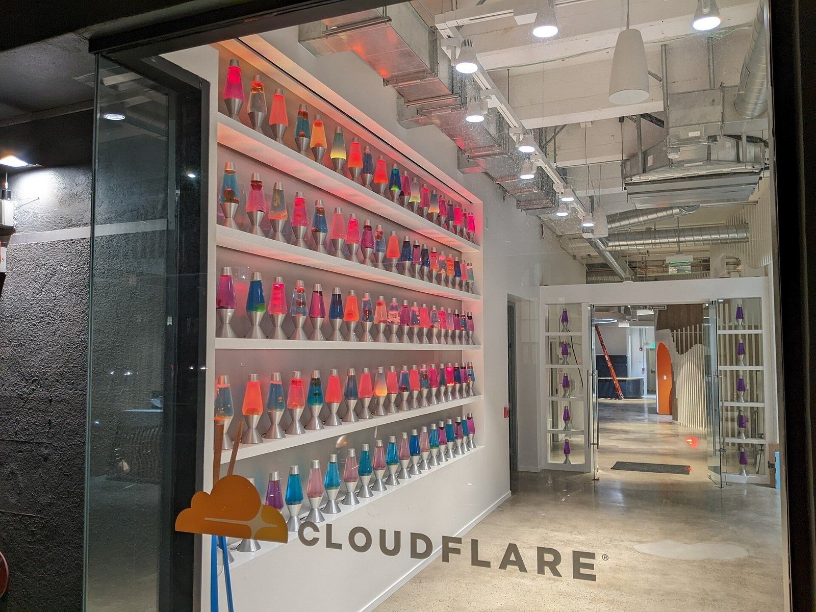 A wall of lava lamps by the glass entrance with the Cloudflare logo