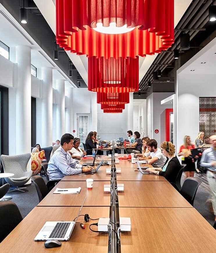 The Coca-Cola Company: A long work table under red pendant lights
