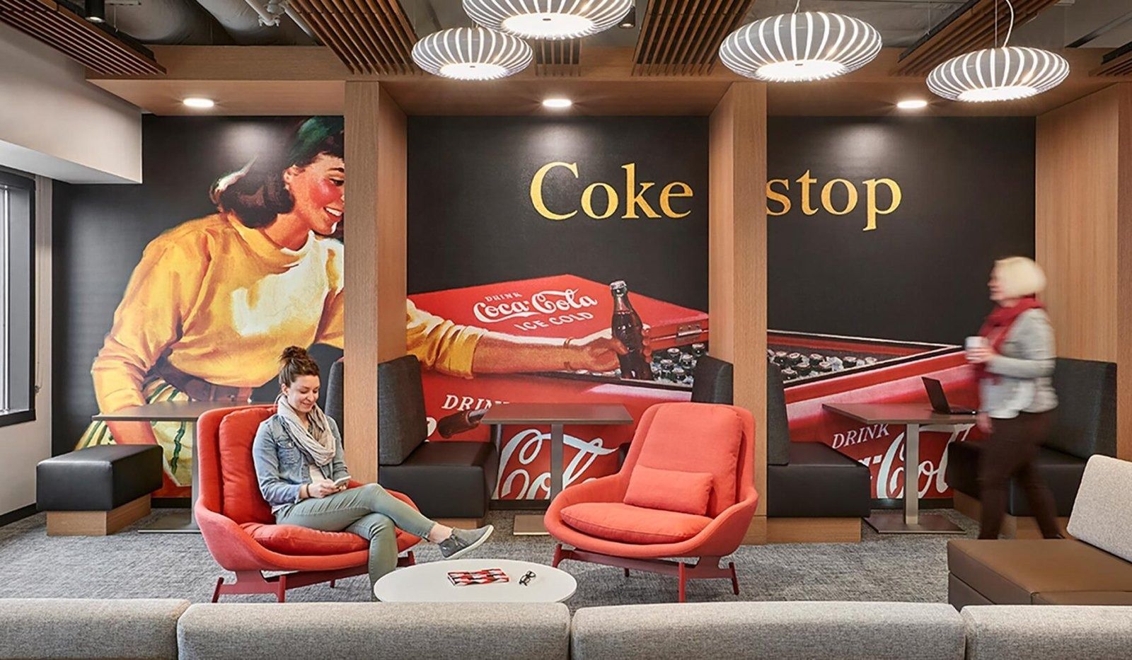 The Coca-Cola Company: A lounge with a vintage Coke advertising mural and red chairs