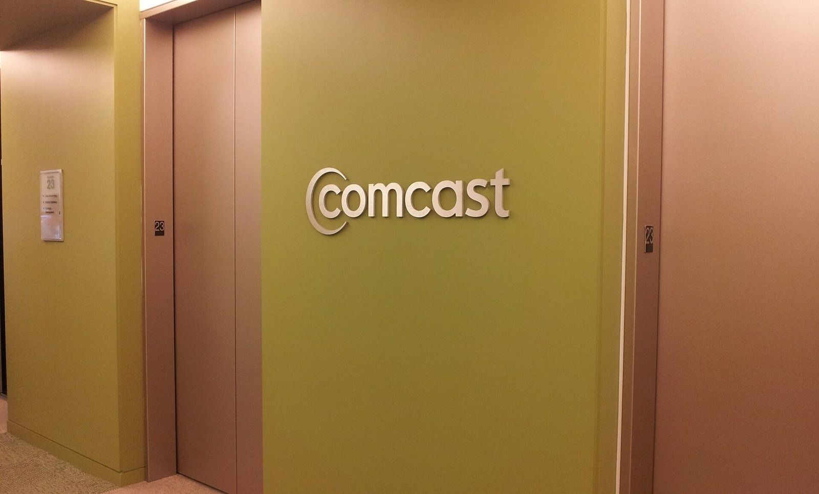 Comcast: Elevator lobby with the Comcast name on a wood wall