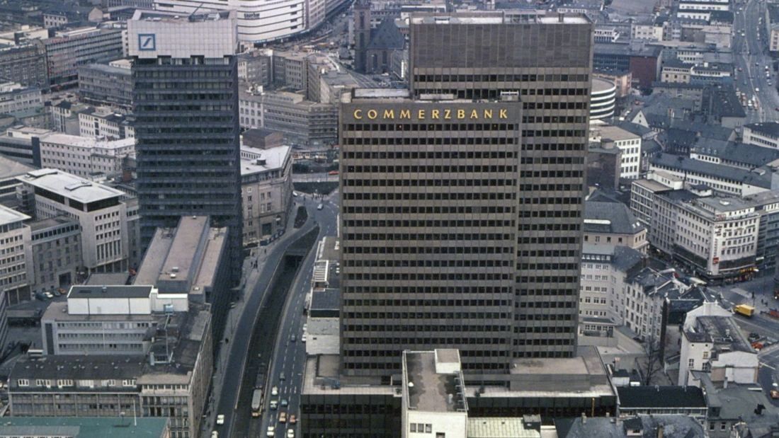 Aerial colour photo of a dark high-rise with the word COMMERZBANK on top, set among city blocks and a road