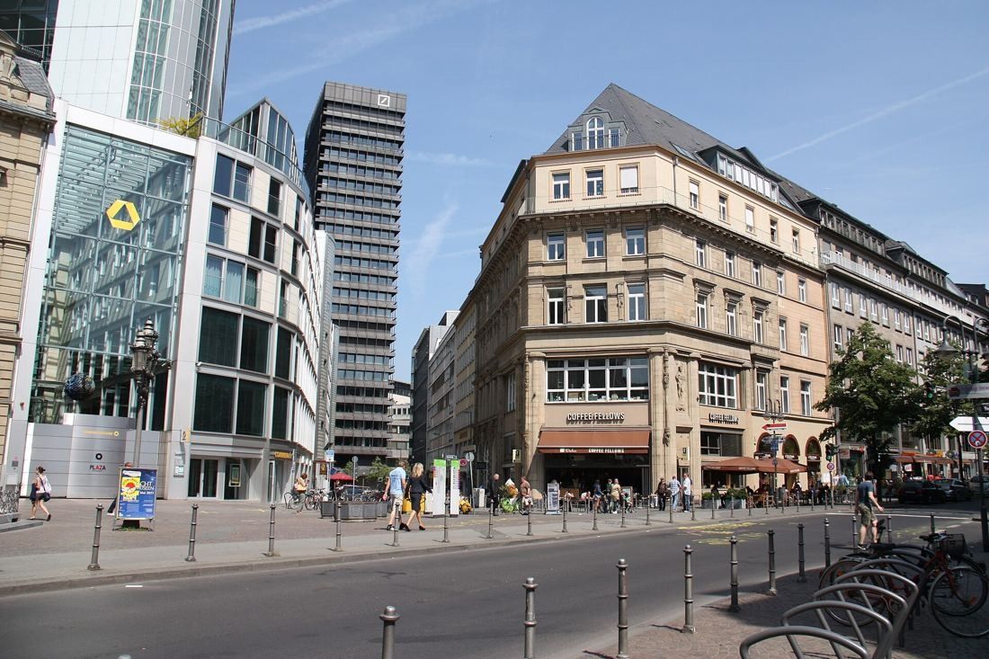 Commerzbank: City square with a glass entrance building on the left, older stone buildings on the right and the tower behind