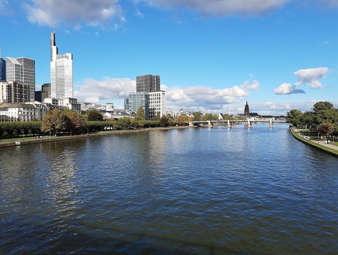 Commerzbank: River view with the city skyline and the tower on the left bank under a blue sky