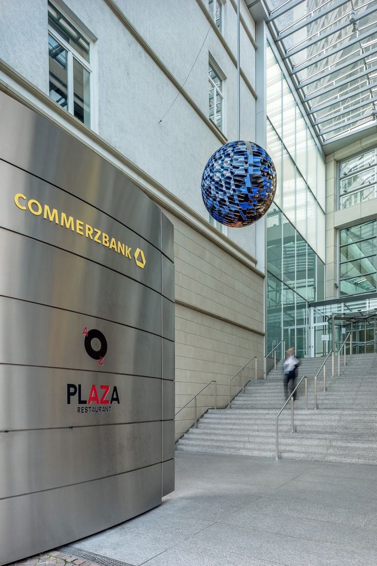 Commerzbank: Steel wall with company lettering, a hanging blue sculptural sphere and wide granite steps up to a glass entrance