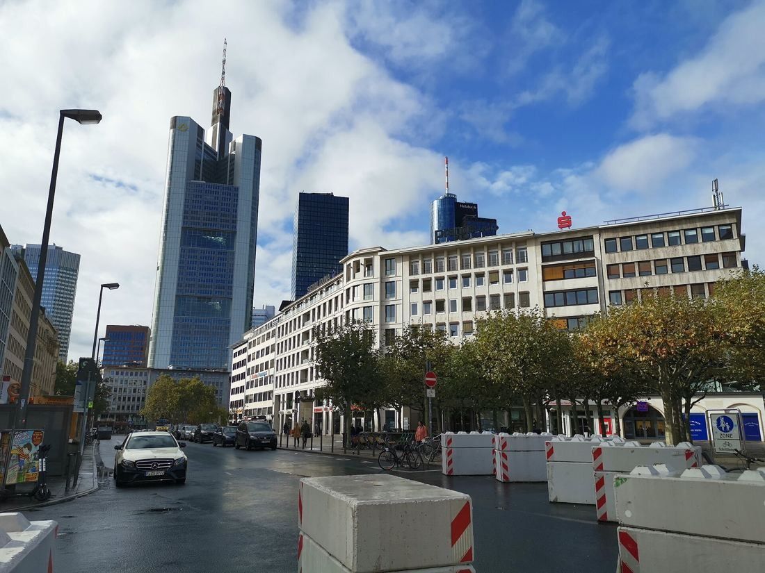 Commerzbank: Street with cars and a stone office building, the tower rising in the background