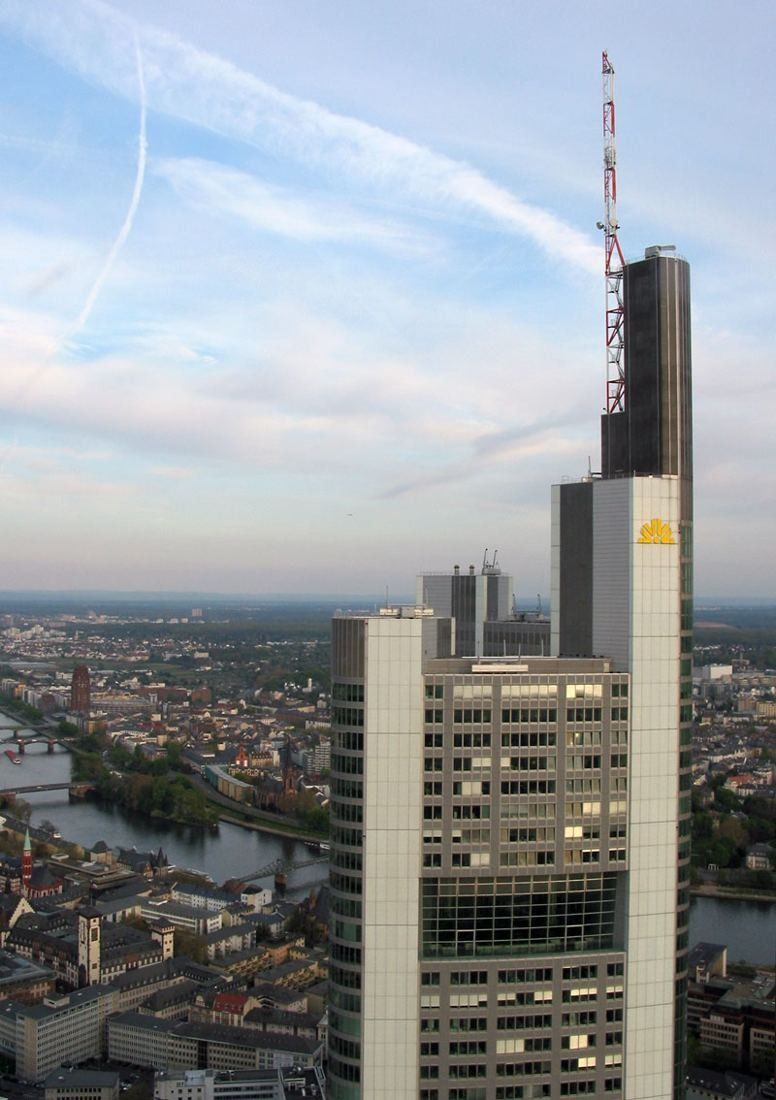 Commerzbank: Top of the tower and its antenna mast seen from a neighbouring high-rise, the city spread out below