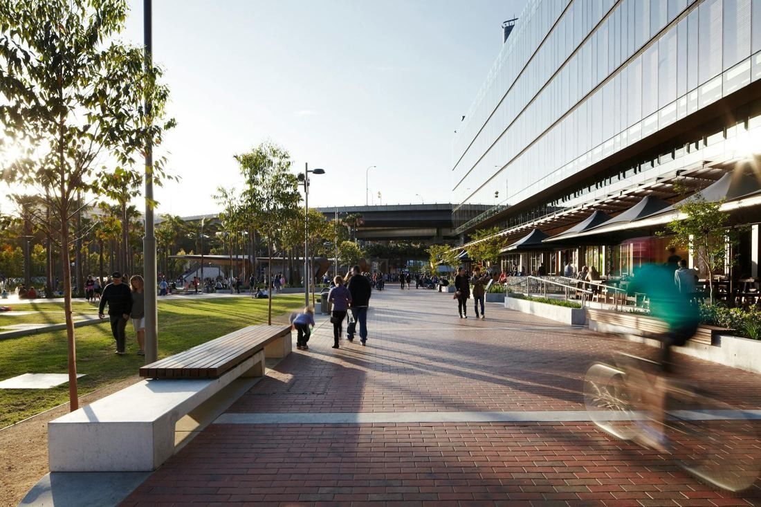 Commonwealth Bank of Australia: Brick-paved walkway with benches running beside a glass office building and a lawn