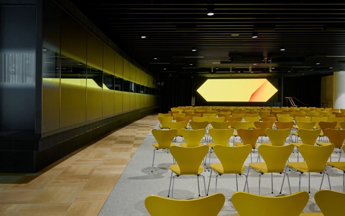 Commonwealth Bank of Australia: Dark auditorium with rows of yellow chairs facing a glowing hexagonal screen