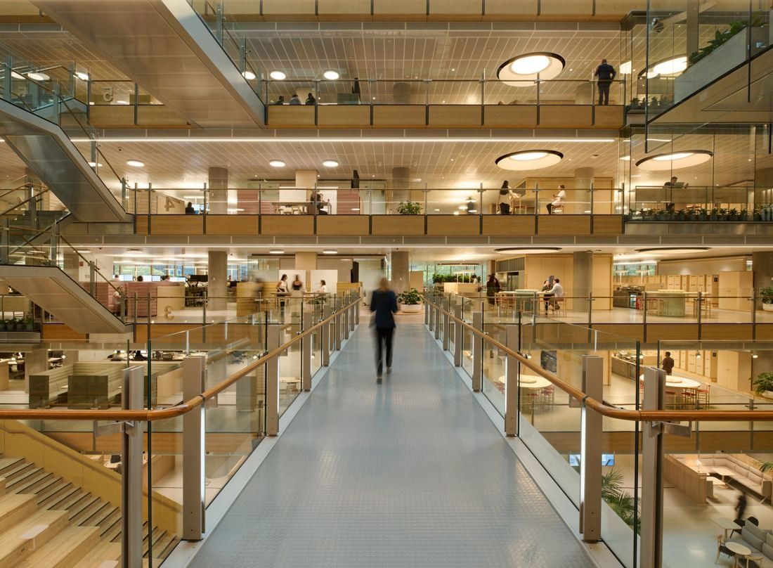 Commonwealth Bank of Australia: Glass bridge crossing a multi-level timber-lined atrium with open office floors on each side