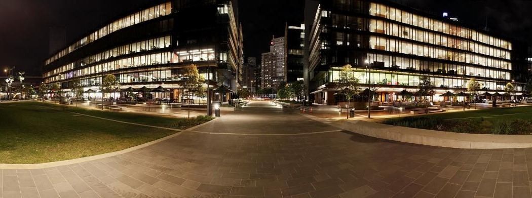 Commonwealth Bank of Australia: Night panorama of two lit office buildings framing a lawn