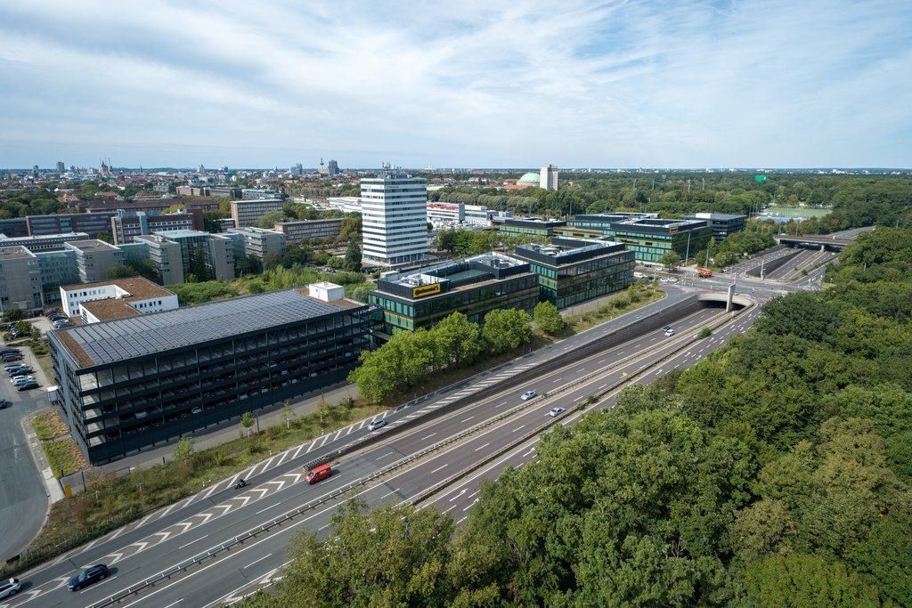 Continental: Aerial view of office buildings beside a motorway and a forest, with the city behind