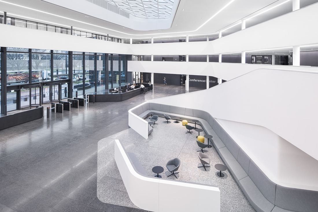 Continental: Atrium seen from above with curved white benches and chairs and a long window wall