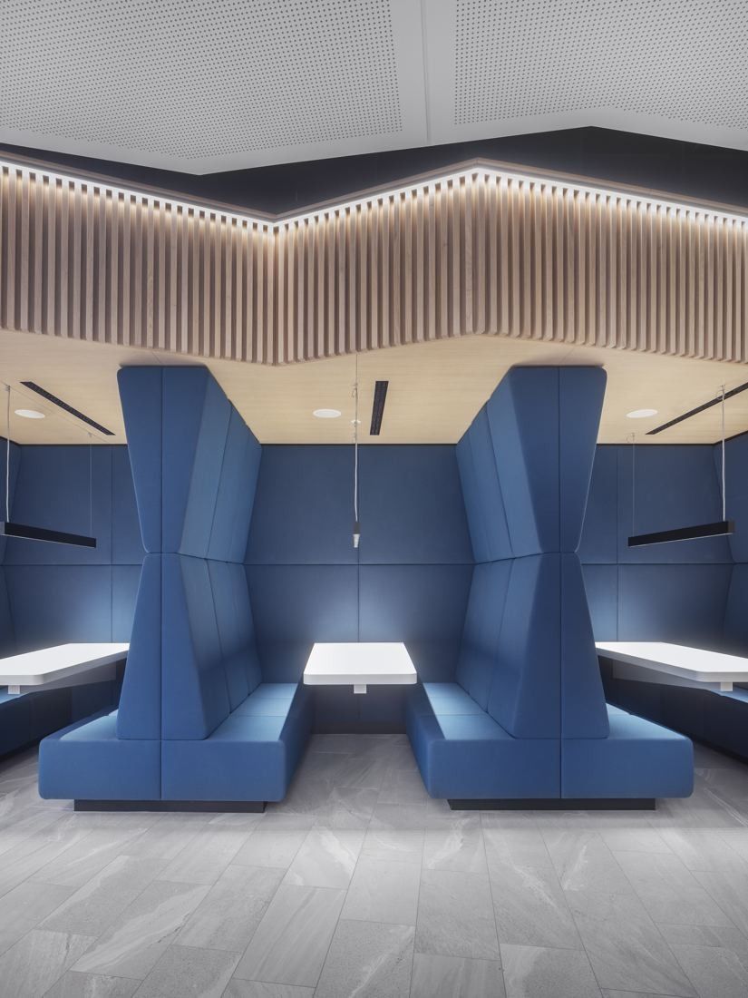 Continental: Blue upholstered high-backed booths with tables under a slatted wooden ceiling