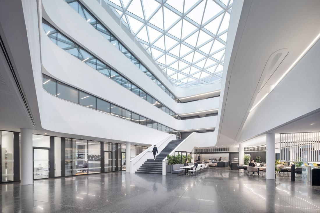 Continental: Bright multi-storey atrium under a glass roof, with white curved balconies and a staircase