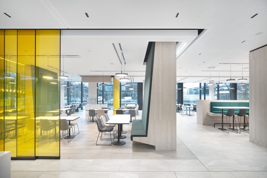 Continental: Café area with a yellow glass panel, tables and chairs and a green bench