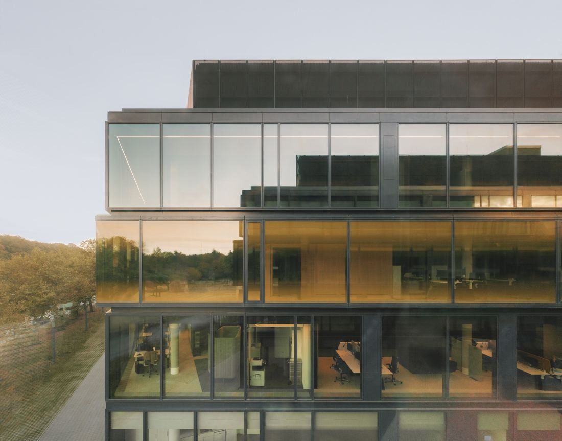 Continental: Corner of a glass office building with lit wooden interiors at dusk
