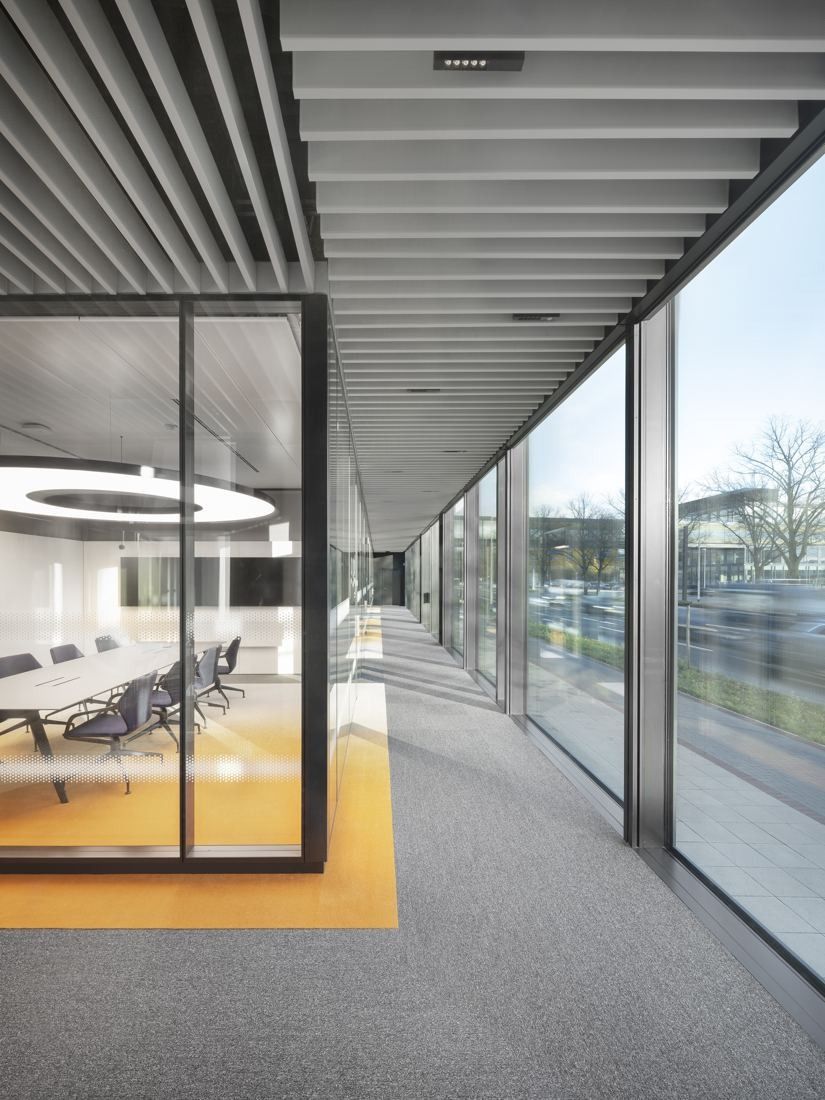 Continental: Corridor along a glass façade next to a glass-walled meeting room with a yellow floor