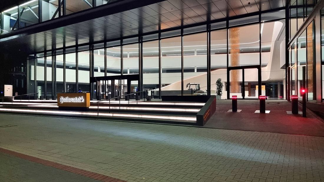 Continental: Glass entrance hall lit at night with wide steps and a small yellow sign