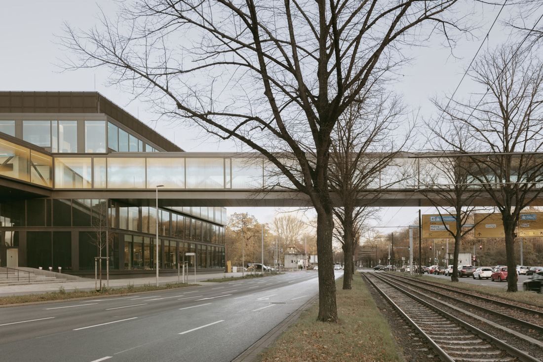 Continental: Glazed bridge crossing a road and tram tracks, with bare trees in front