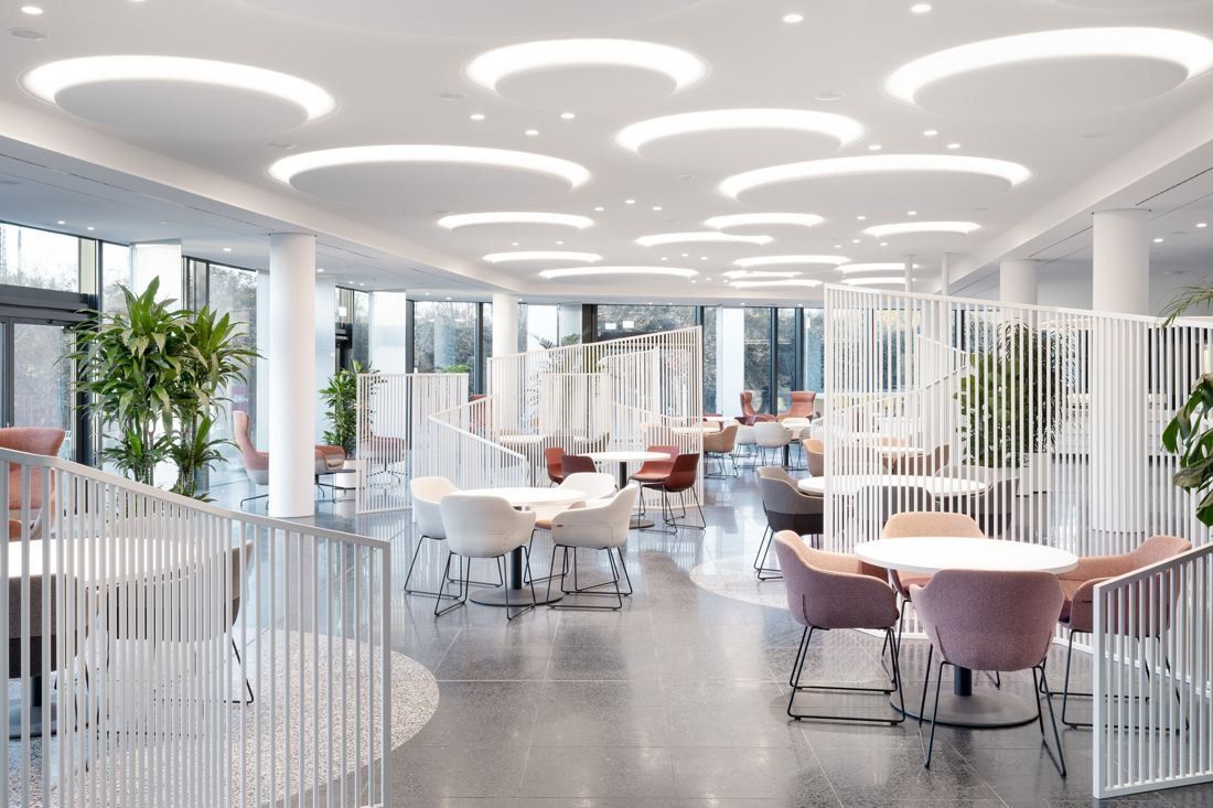 Continental: Large dining area with round tables, pink chairs, plants and circular ceiling lights