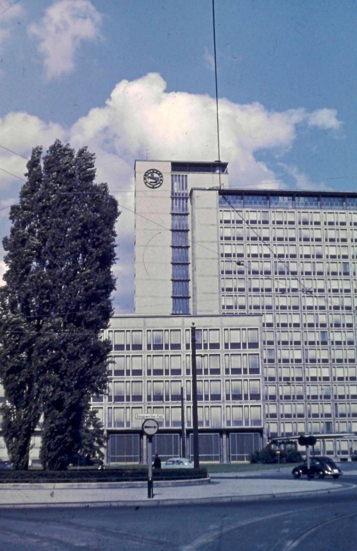 Multi-storey office tower with a clock on top under a cloudy sky