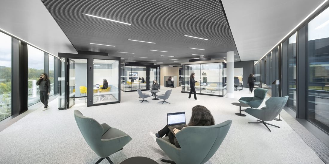Continental: Open area with green lounge chairs and glass-walled meeting boxes between window walls