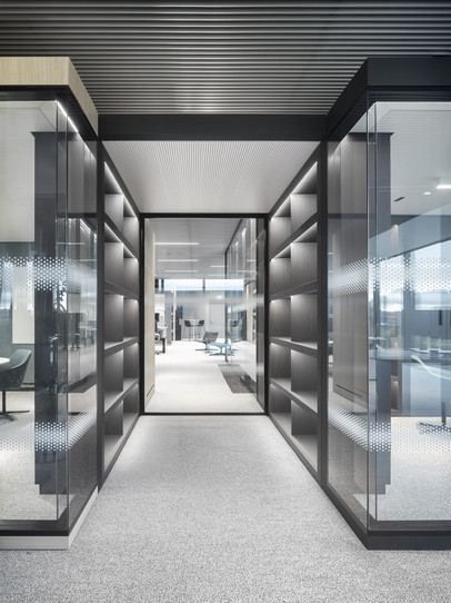 Continental: Passage between dark glass-walled rooms leading to an open office
