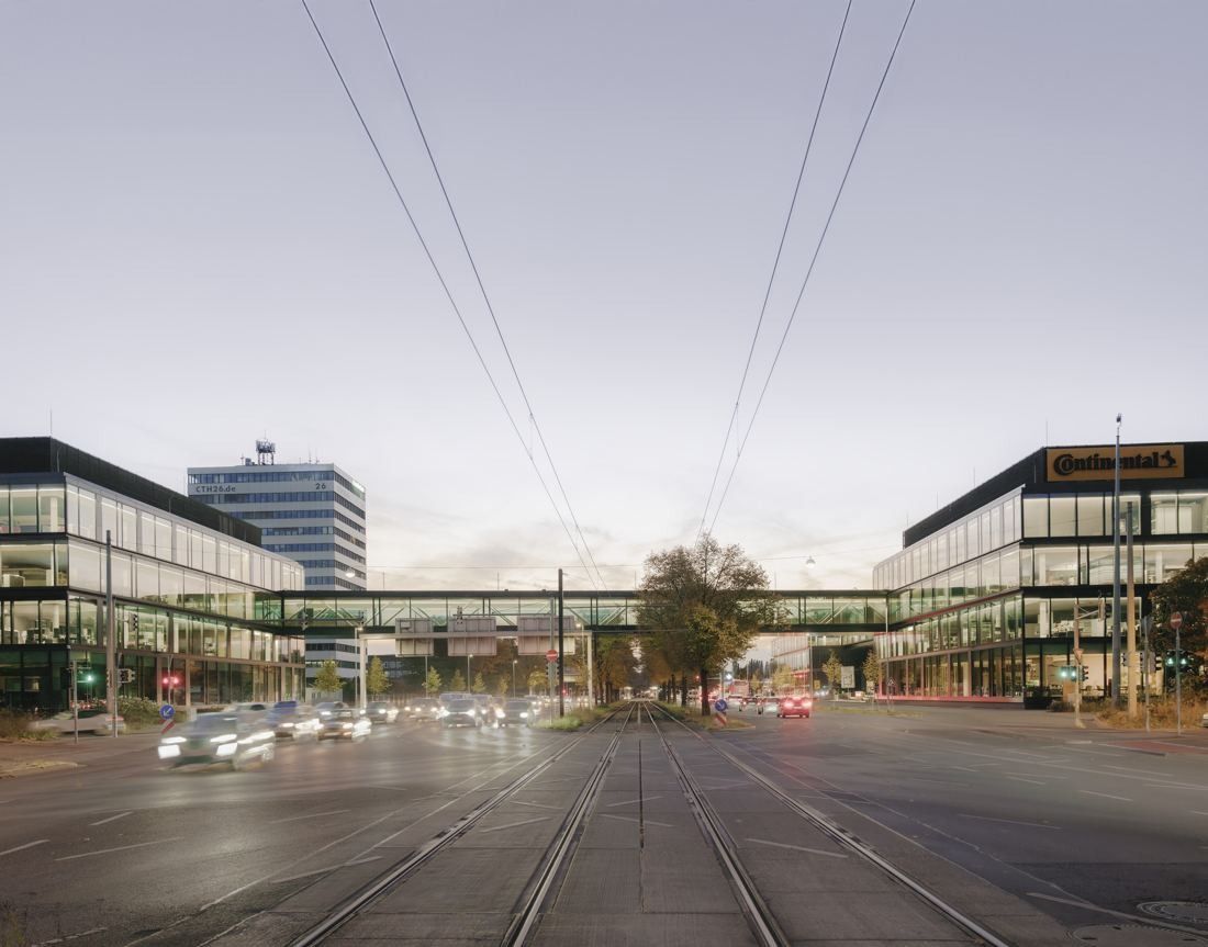 Continental: View down a wide road with tram tracks towards a glazed bridge linking office buildings on both sides