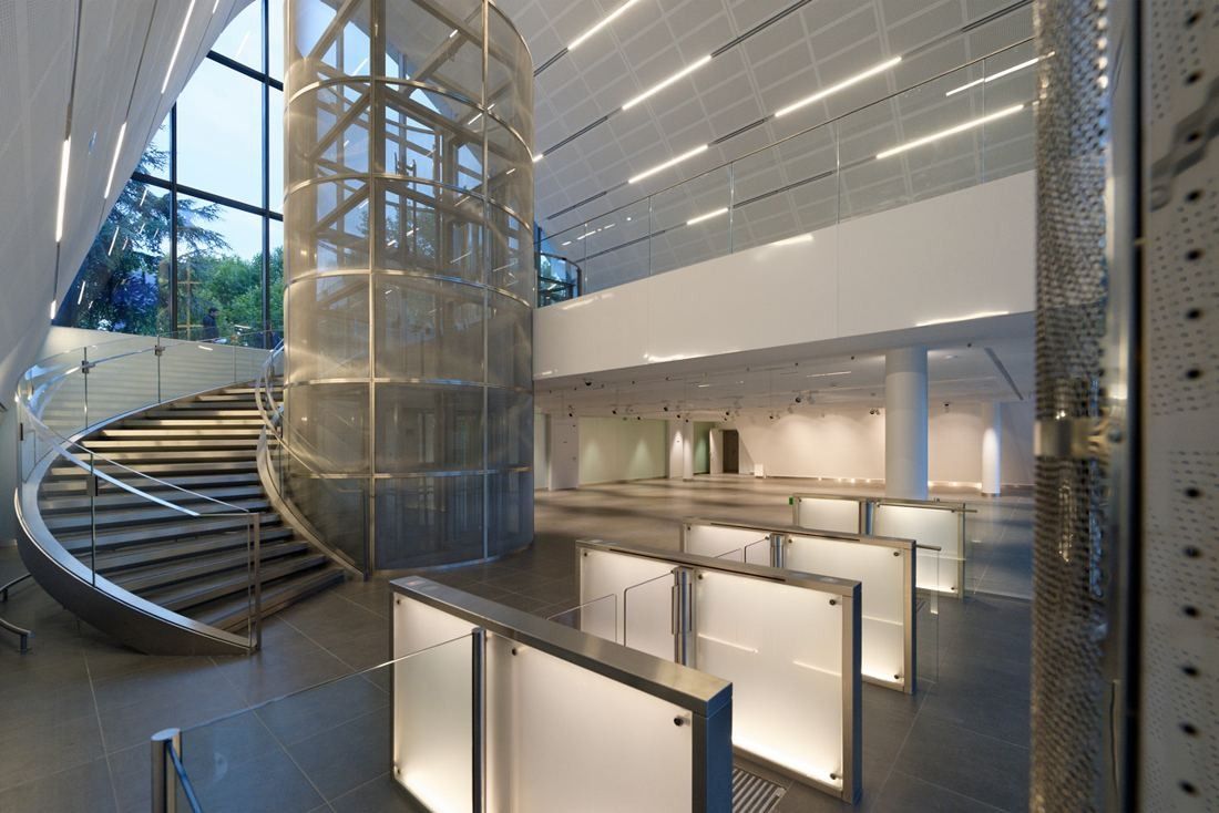 Crédit Agricole: A bright hall with a spiral staircase, a glass lift shaft and glass entry gates