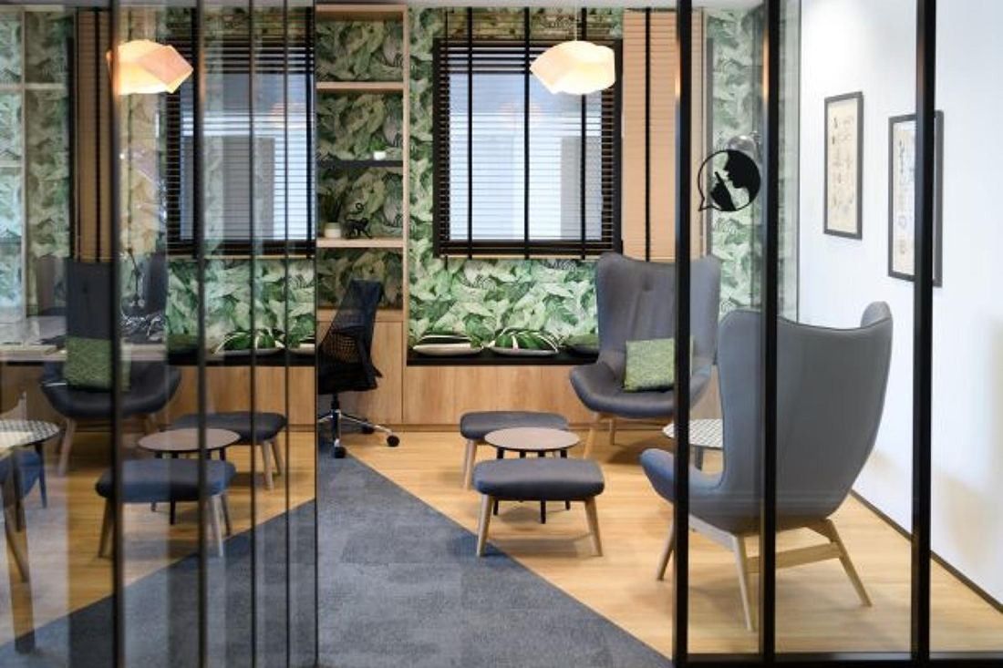 Crédit Agricole: A glazed lounge with armchairs, small tables and leaf-print wallpaper