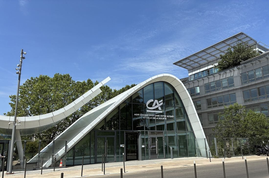 Crédit Agricole: A glazed pavilion with a white wave-shaped roof in front of an office building