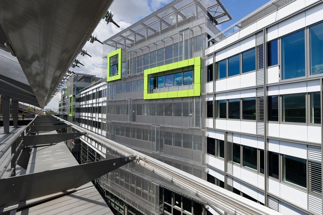 Crédit Agricole: A grey and white facade with lime-green window frames seen from a walkway
