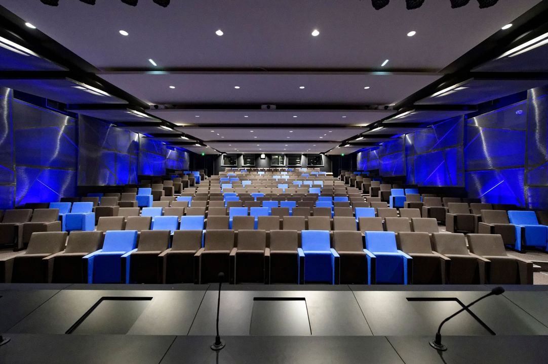 Crédit Agricole: A large auditorium with rows of grey and blue seats and blue-lit walls