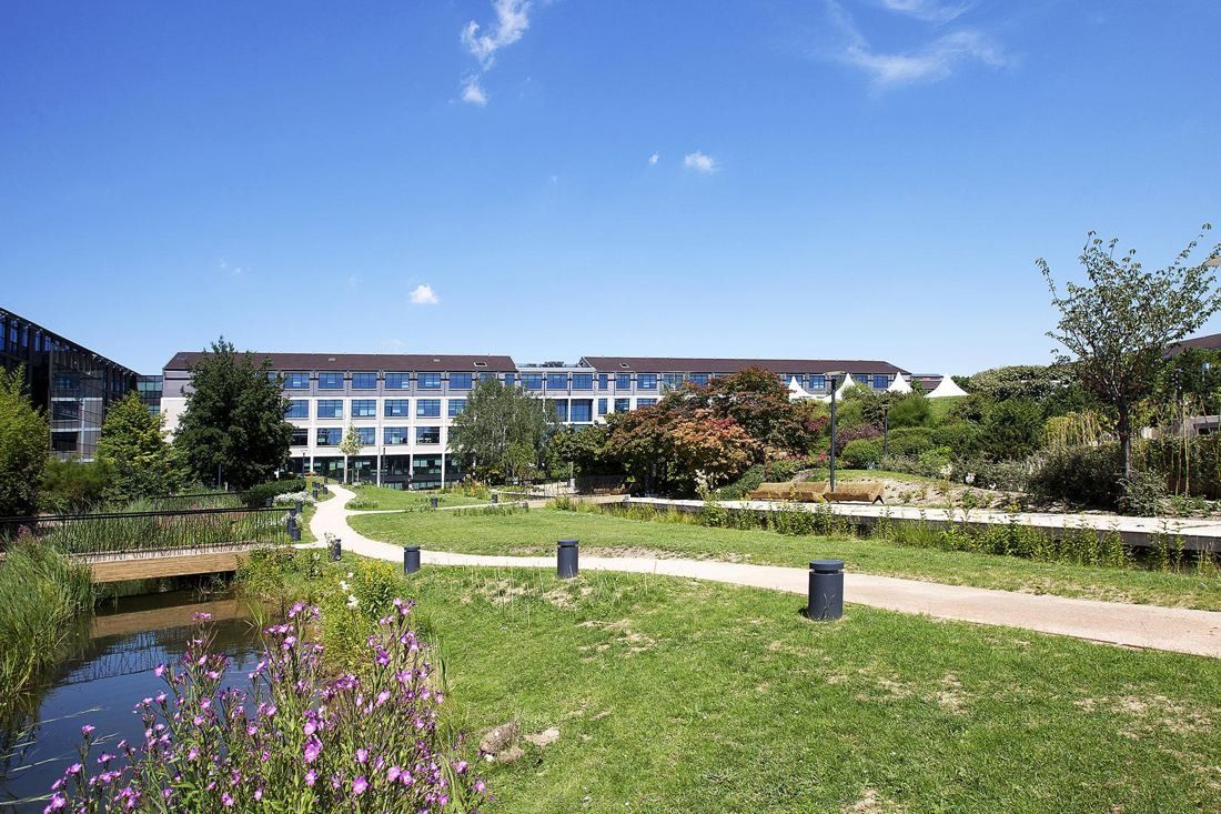 Crédit Agricole: A lawn and pond with wild flowers in front of a long office building