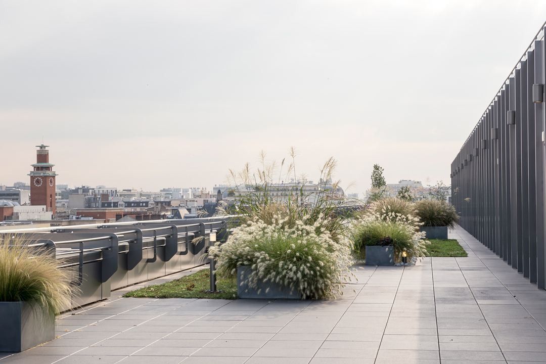 Crédit Agricole: A paved roof terrace with planters of grasses and a city view