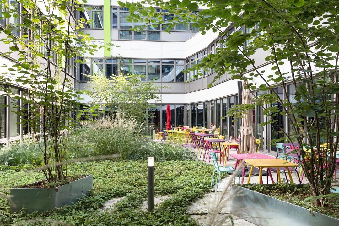Crédit Agricole: A planted courtyard with trees and colourful café tables between glazed office walls